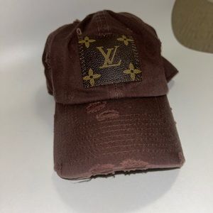 A brown distressed hat with a Louis Vutton piece of leather on the front